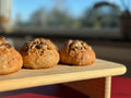 Gluten-free vegan boller with mixed seeds on a wooden board, the Danish bread buns baked by Gluten Tag in Copenhagen.