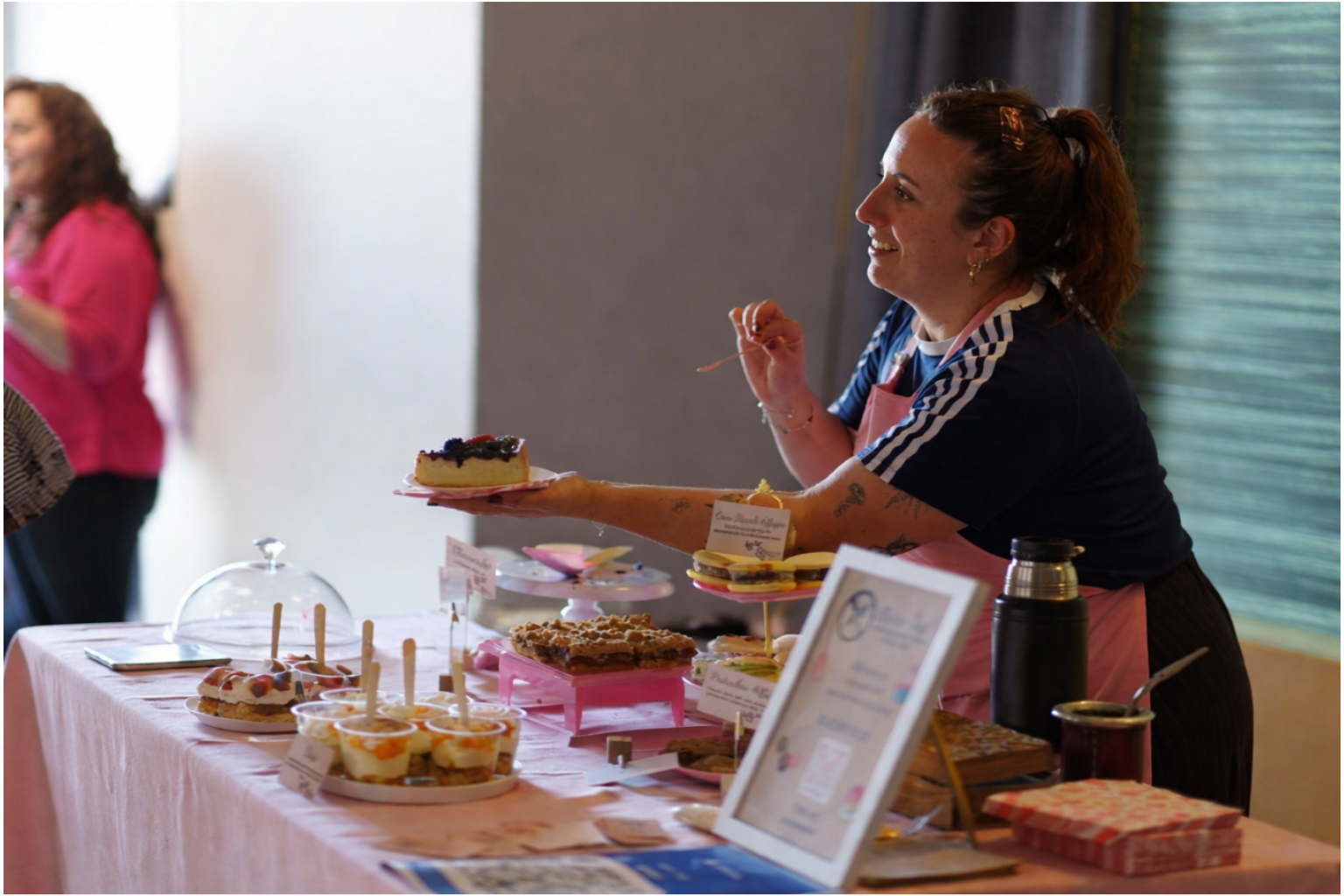 Founder of Gluten Tag presenting a selection of gluten free baked goods at a Copenhagen market, including layer cakes, alfajores and individual desserts