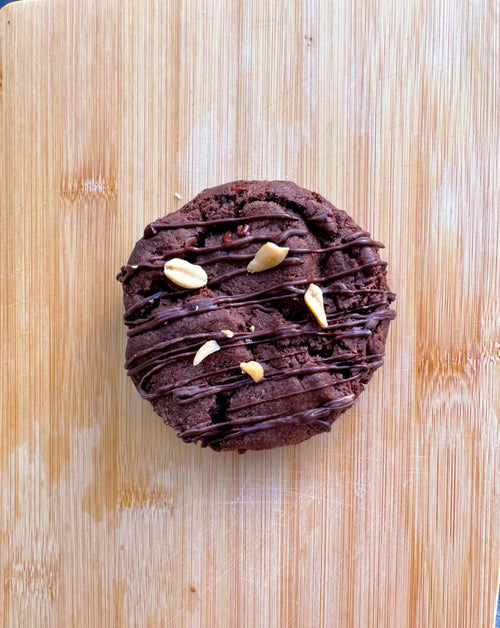Vegan gluten-free cookie broken in half showing creamy peanut butter center and dark chocolate chips, baked Levain-style by Gluten Tag in Copenhagen.